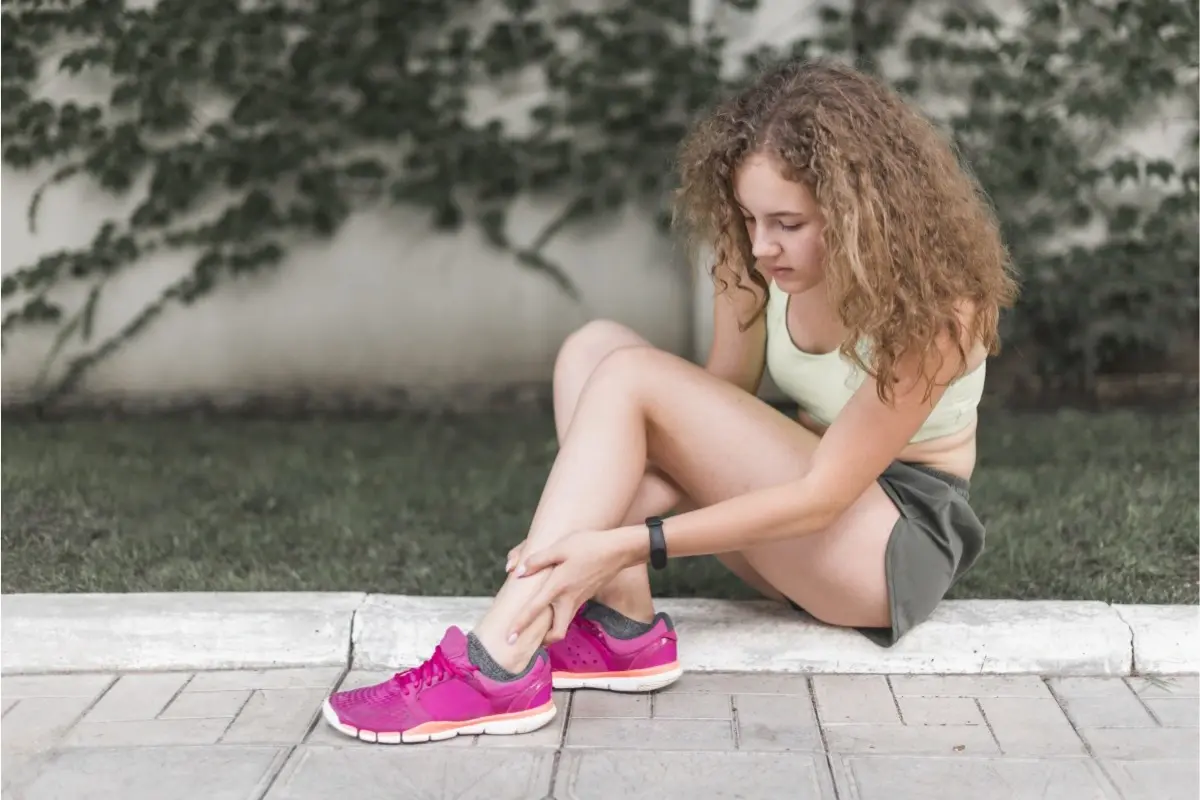 Dievča si drží píšťalu pri bolesti holennej kosti po behu – syndróm holennej kosti